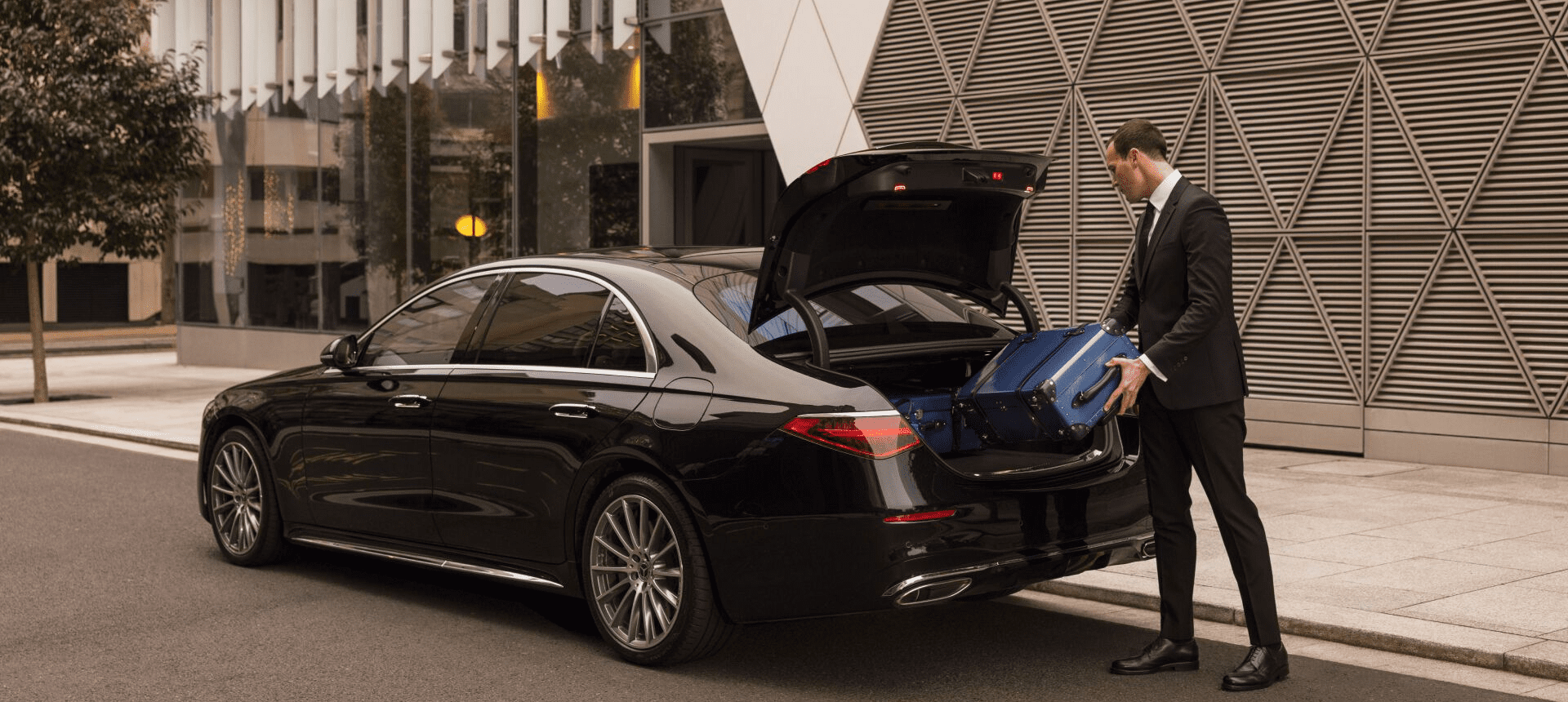 Comfy Ride professional chauffeur assisting with luggage beside executive car
